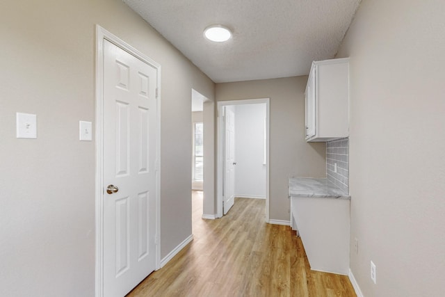 hallway featuring light hardwood / wood-style flooring and a textured ceiling