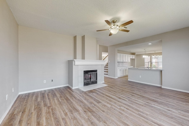 unfurnished living room with ceiling fan, light wood-type flooring, and a textured ceiling