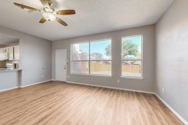 unfurnished living room featuring a textured ceiling, light hardwood / wood-style floors, and plenty of natural light