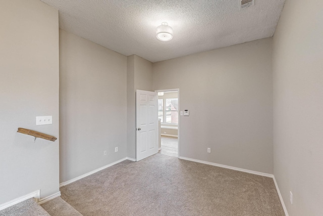 carpeted empty room with a textured ceiling