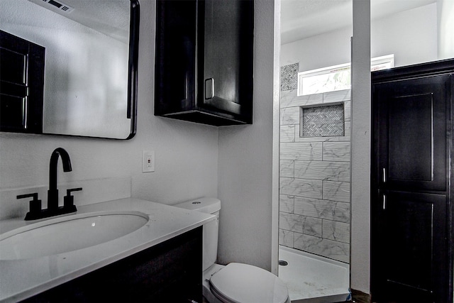 bathroom featuring walk in shower, vanity, toilet, and a textured ceiling