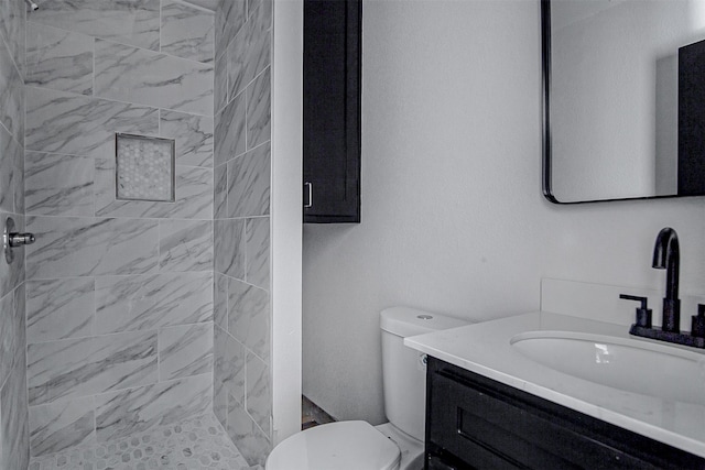 bathroom featuring tiled shower, vanity, and toilet