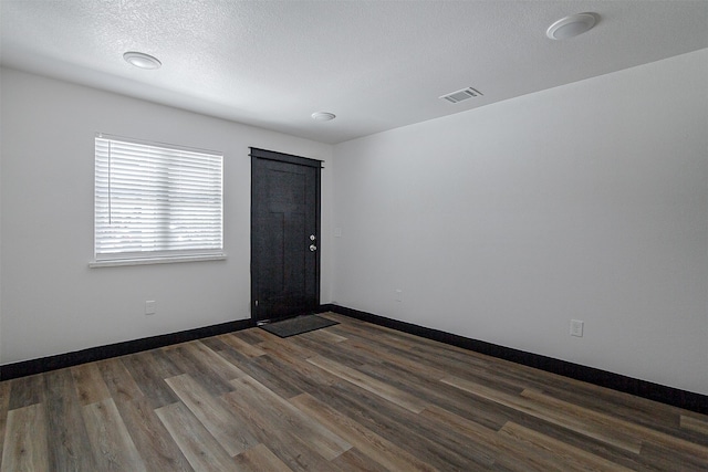 unfurnished room with a textured ceiling and dark hardwood / wood-style flooring