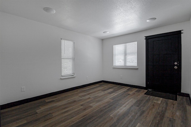 empty room with a textured ceiling and dark hardwood / wood-style floors