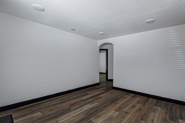 spare room with a textured ceiling and dark hardwood / wood-style flooring