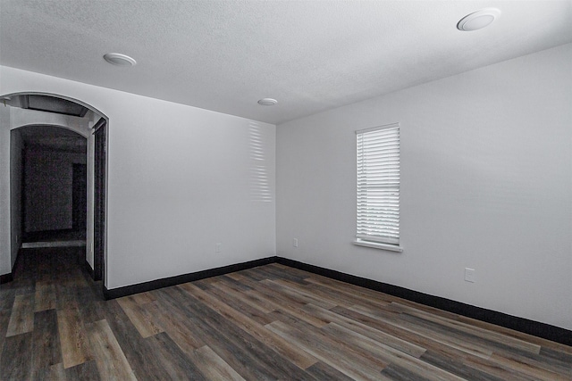 unfurnished room featuring a textured ceiling and dark hardwood / wood-style floors