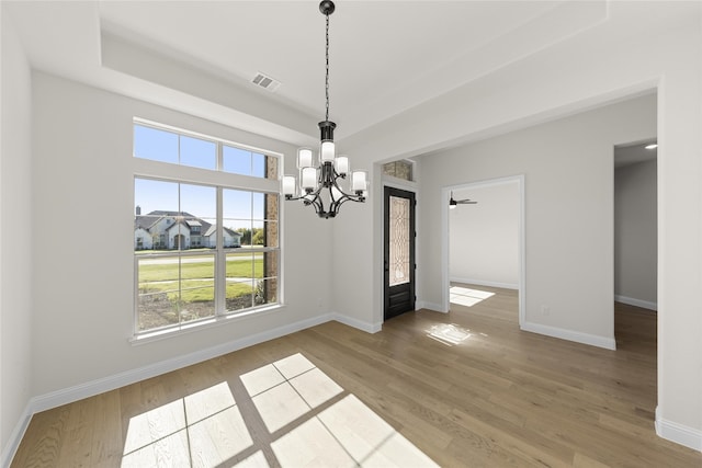 unfurnished dining area featuring baseboards, visible vents, and wood finished floors