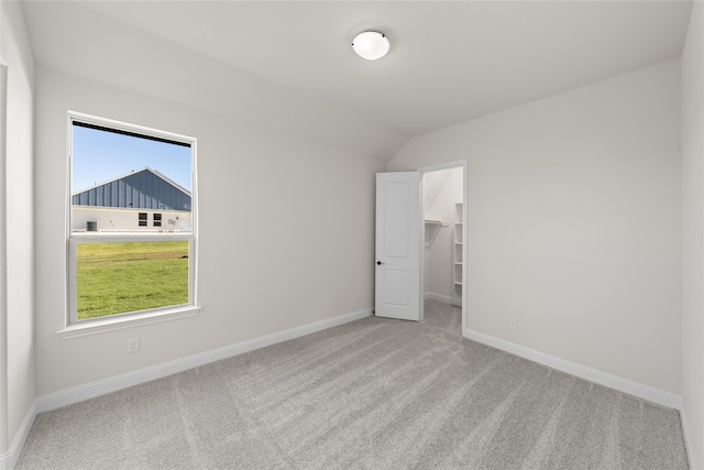 empty room with light carpet and vaulted ceiling