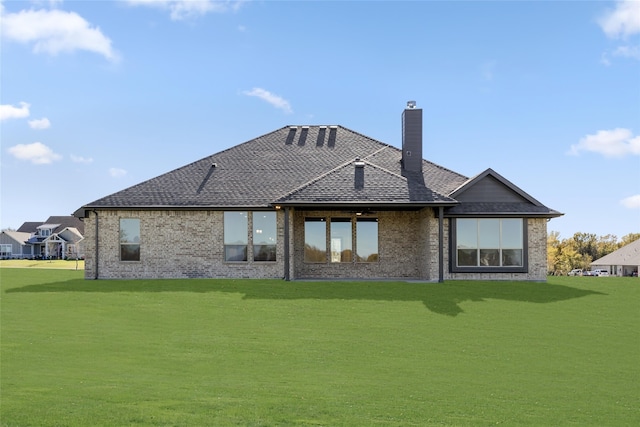 back of property with brick siding, a lawn, a chimney, and a shingled roof