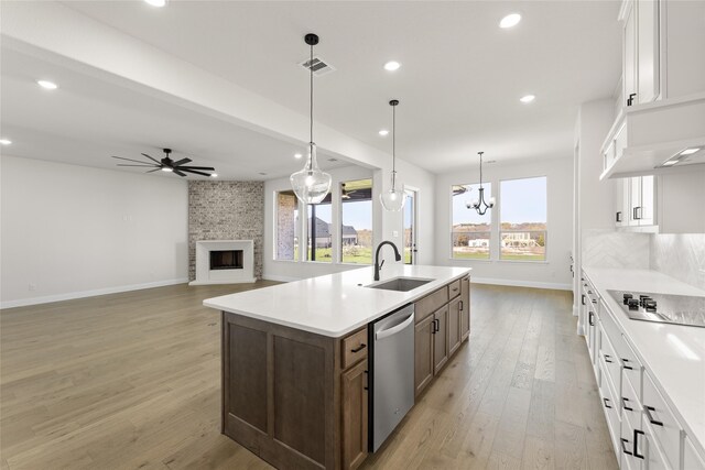 kitchen featuring light wood-type flooring, stainless steel appliances, sink, a center island with sink, and white cabinets