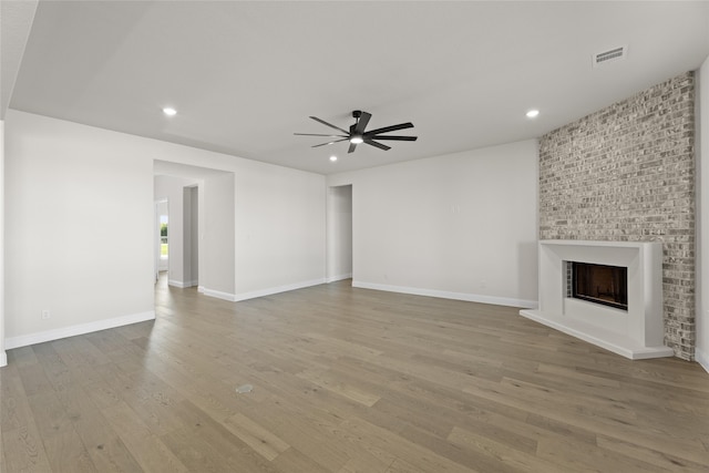 unfurnished living room with ceiling fan, recessed lighting, a large fireplace, visible vents, and light wood finished floors