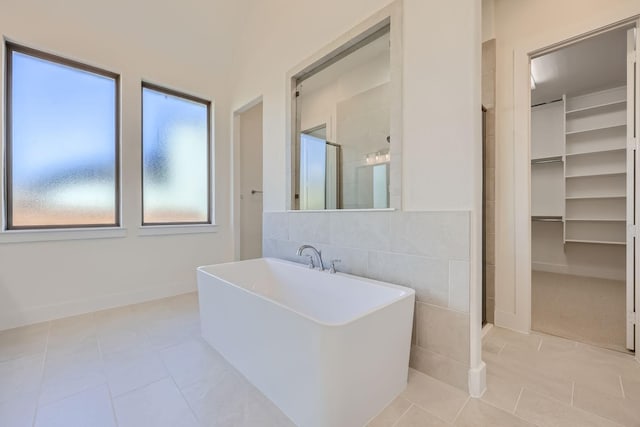 bathroom with tile patterned flooring, tile walls, and independent shower and bath