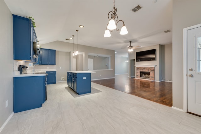 kitchen featuring blue cabinets, light wood-type flooring, decorative light fixtures, a fireplace, and a center island