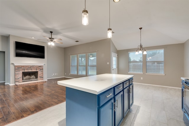 kitchen with light hardwood / wood-style floors, blue cabinets, decorative light fixtures, a fireplace, and a center island