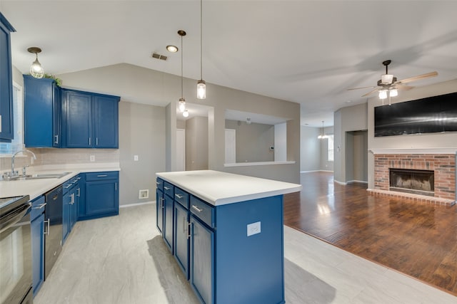 kitchen with light hardwood / wood-style floors, blue cabinetry, a kitchen island, sink, and decorative backsplash