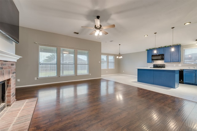 unfurnished living room with ceiling fan with notable chandelier, a fireplace, and dark wood-type flooring