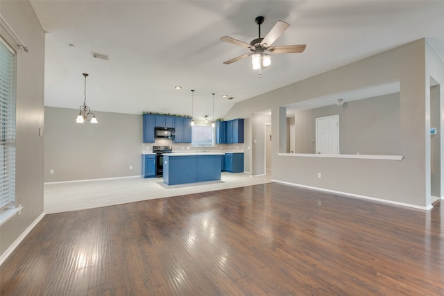 unfurnished living room featuring dark wood-type flooring, ceiling fan with notable chandelier, and vaulted ceiling