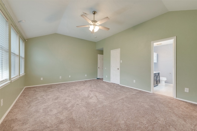 unfurnished bedroom with ceiling fan, light colored carpet, ensuite bath, and vaulted ceiling