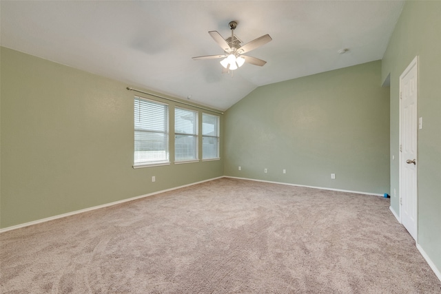 empty room with ceiling fan, vaulted ceiling, and light colored carpet