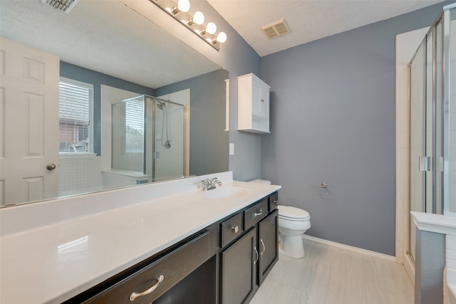 bathroom featuring vanity, a shower with door, toilet, and a textured ceiling