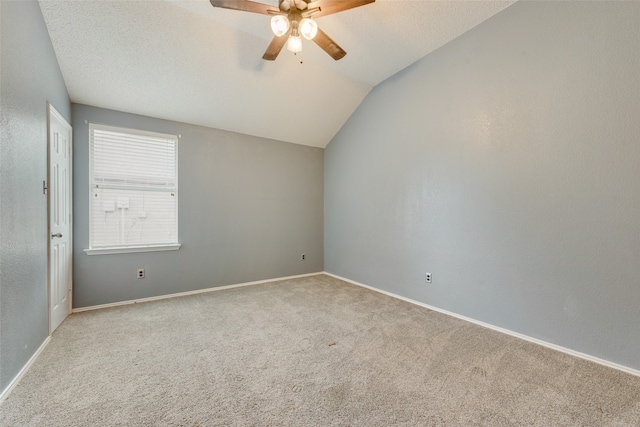 empty room featuring a textured ceiling, lofted ceiling, ceiling fan, and light colored carpet