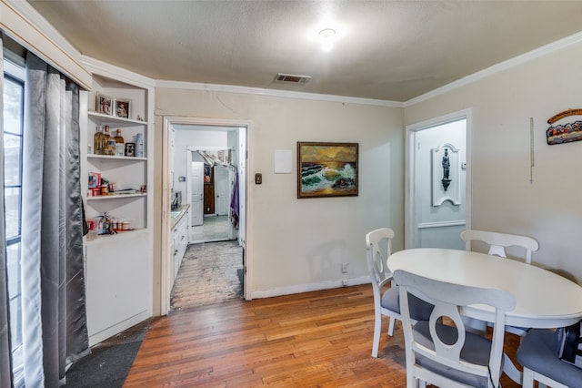 dining room featuring a textured ceiling, crown molding, and hardwood / wood-style flooring