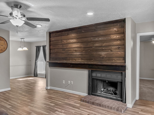 unfurnished living room with hardwood / wood-style floors, a fireplace, a textured ceiling, and ceiling fan