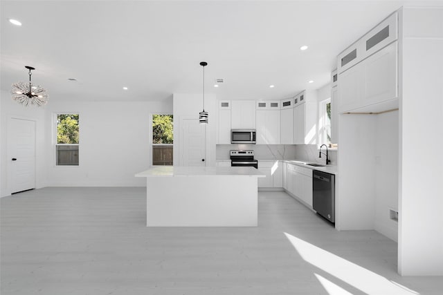 309 W Beckham St W, Sulphur Springs, TX 75482 - kitchen featuring appliances with stainless steel finishes, a chandelier, white cabinetry, glass insert cabinets, and light countertops