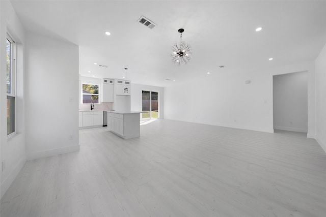 309 W Beckham St W, Sulphur Springs, TX 75482 - unfurnished living room with a chandelier, light wood-style flooring, recessed lighting, a sink, and baseboards