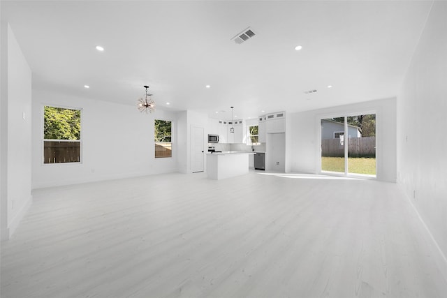 309 W Beckham St W, Sulphur Springs, TX 75482 - unfurnished living room featuring a chandelier, recessed lighting, light wood-type flooring, healthy amount of natural light, and baseboards