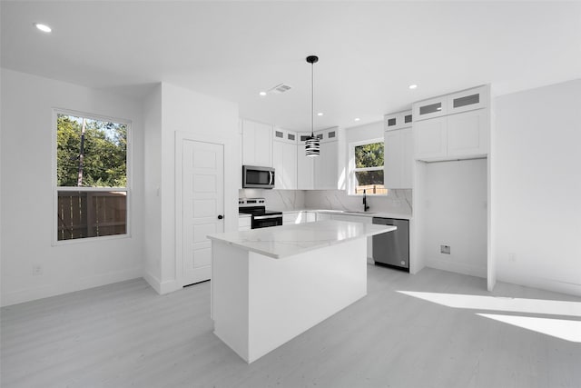 309 W Beckham St W, Sulphur Springs, TX 75482 - kitchen featuring appliances with stainless steel finishes, a sink, light wood-type flooring, a kitchen island, and glass insert cabinets