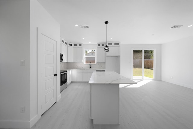 309 W Beckham St W, Sulphur Springs, TX 75482 - kitchen featuring appliances with stainless steel finishes, a sink, light wood-style flooring, a kitchen island, and backsplash