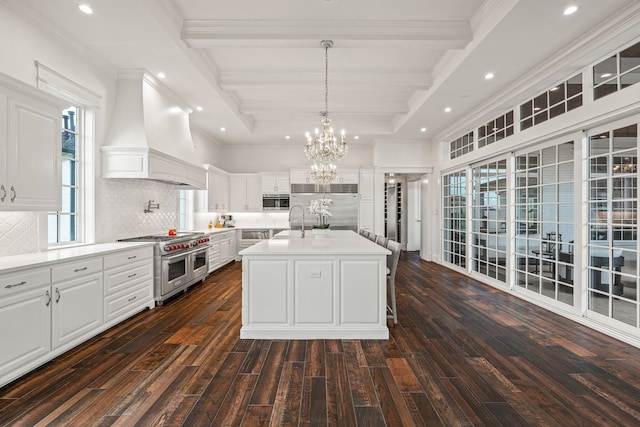 kitchen with white cabinetry, a kitchen island with sink, custom range hood, high end appliances, and pendant lighting