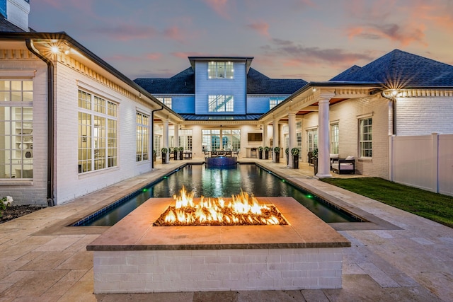 pool at dusk with a patio and an outdoor fire pit