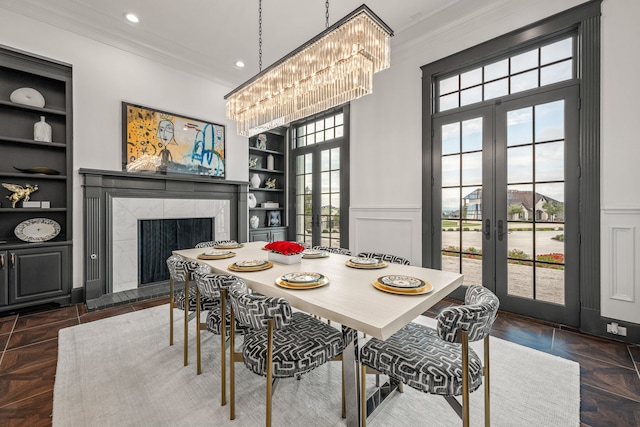 dining room featuring a fireplace, ornamental molding, built in shelves, and french doors