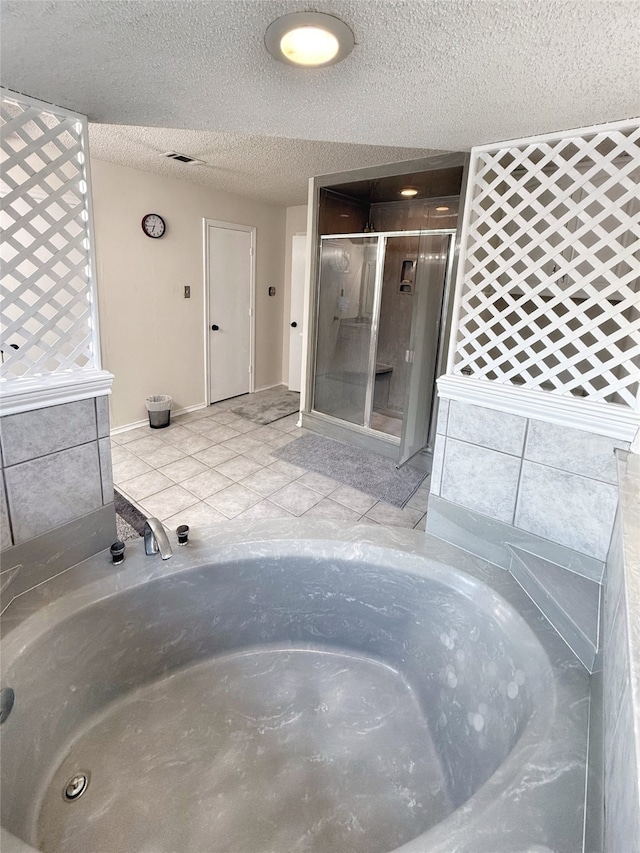 bathroom with independent shower and bath, a textured ceiling, and tile patterned flooring