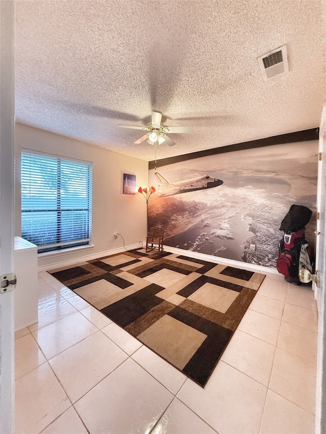 interior space with ceiling fan, a textured ceiling, and tile patterned floors