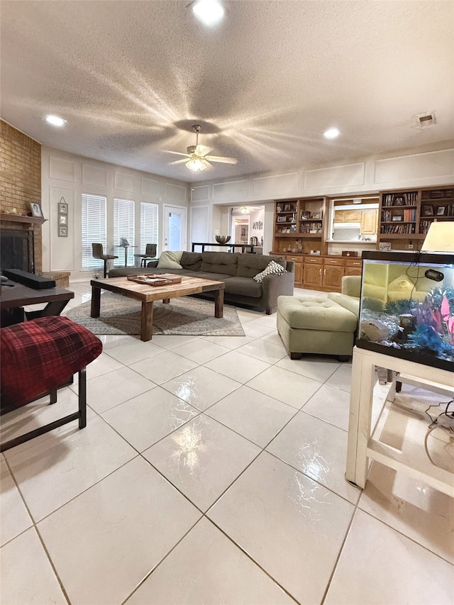 tiled living room with ceiling fan, a fireplace, and a textured ceiling