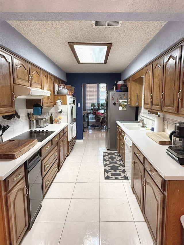 kitchen featuring stainless steel appliances, a textured ceiling, and light tile patterned floors