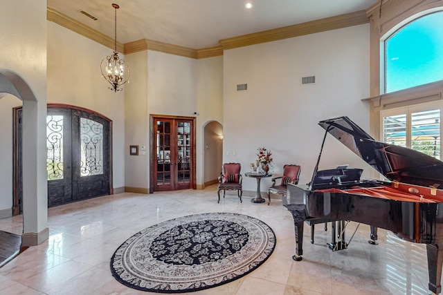 entrance foyer featuring french doors, crown molding, a chandelier, and a towering ceiling