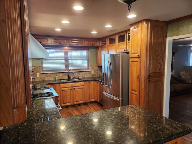 kitchen with appliances with stainless steel finishes, hardwood / wood-style flooring, sink, and ventilation hood