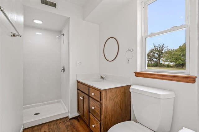 bathroom featuring wood-type flooring, a shower, vanity, and toilet