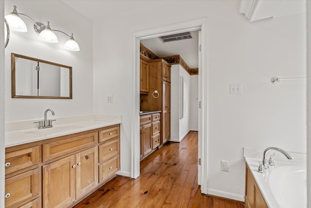 bathroom with vanity, hardwood / wood-style floors, and a bath