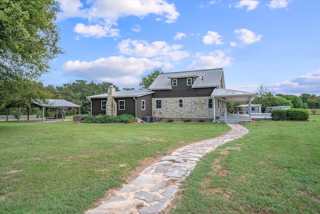 rear view of house featuring central AC, a gazebo, and a yard