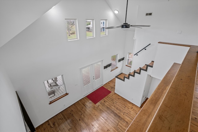 stairway featuring wood-type flooring, high vaulted ceiling, and ceiling fan