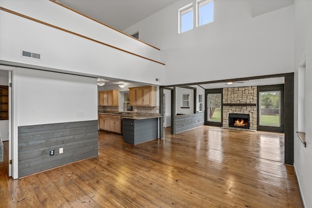 unfurnished living room featuring a high ceiling, a fireplace, sink, and hardwood / wood-style flooring