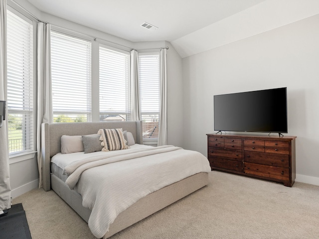 bedroom with multiple windows, light colored carpet, and lofted ceiling