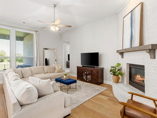 living room featuring ceiling fan, hardwood / wood-style floors, and a brick fireplace