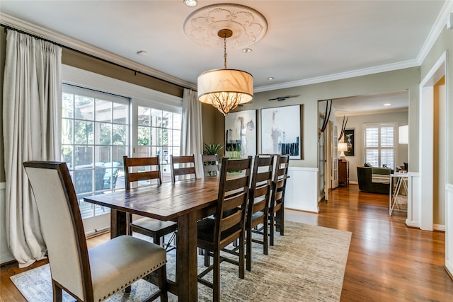 dining space with wood-type flooring, crown molding, and a chandelier