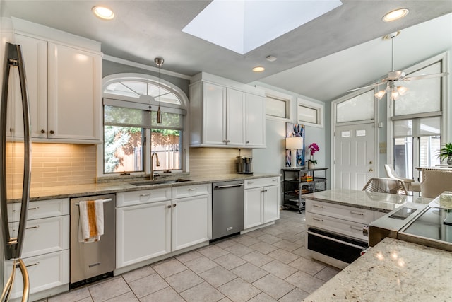 kitchen with ceiling fan, pendant lighting, sink, white cabinetry, and light stone countertops